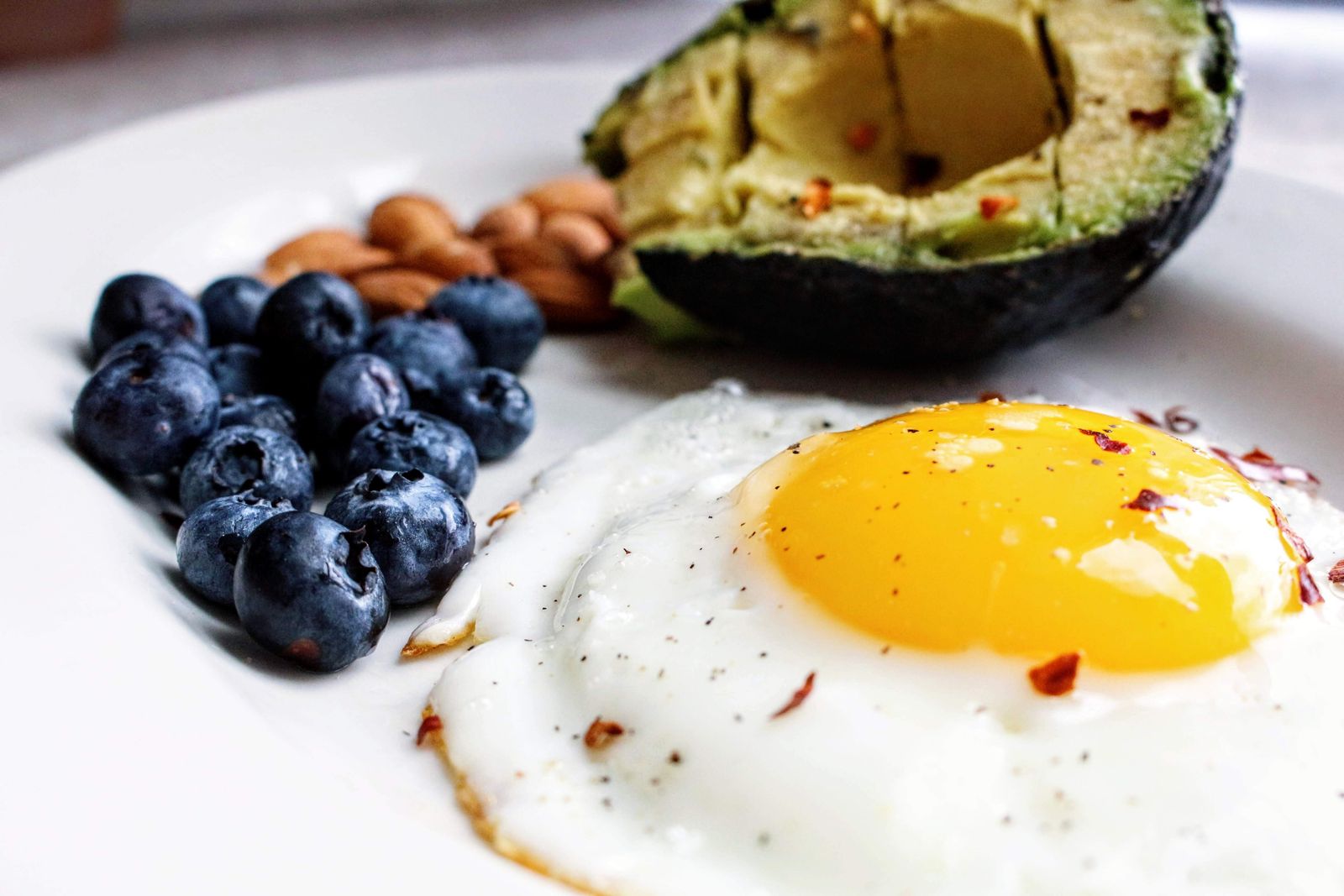 Desayuno con huevo, aguacate y fruta sobre un plato