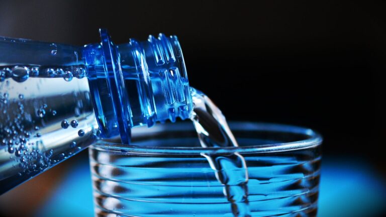 Vaso de agua sobre una mesa junto a una jarra